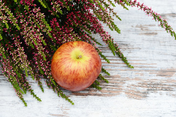 Apple and heather lying on wood