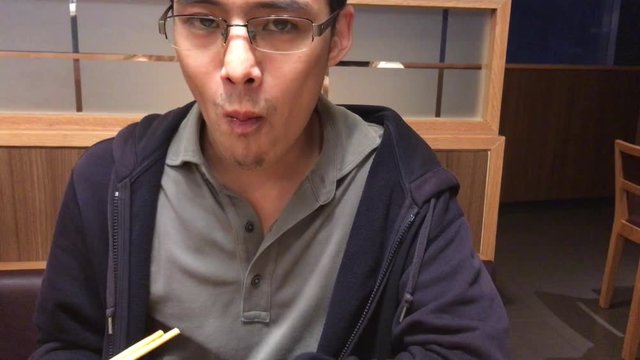 Asian male eat Japanese fried steamed dumplings on dish closeup with chopsticks