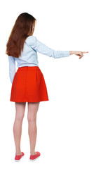 Back view of  pointing woman. beautiful girl. Rear view people collection.  backside view of person.  Isolated over white background. girl in red short skirt shows a finger to the side.