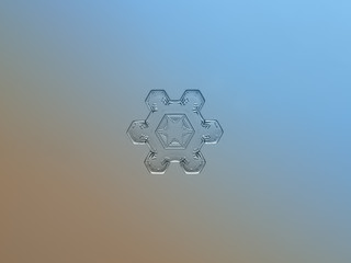 Snowflake on bright blue-brown gradient background. This is macro photo of real snow crystal with short arms and relief surface.