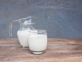 Fresh milk in jar and glass on wooden table