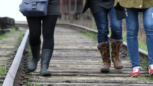Young females walking railway track, medium shot, low angle