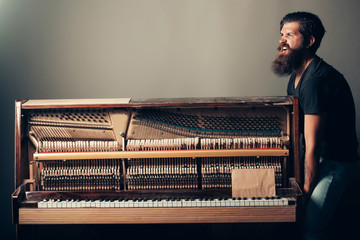 bearded man trying to move wooden piano