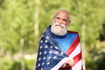 Elderly man with American flag in a park