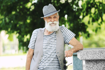 Elderly bearded man in stylish clothes on sunny day at park