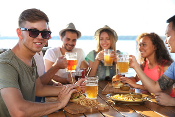 Group of friends drinking beer and eating snacks outdoors