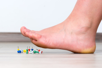 Female foot above colored pushpin