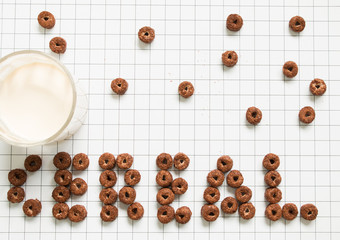 Top view of chocolate cereal typography with milk on grid pattern background.