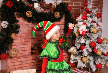 Little girl in suit of the Christmas Elf with old lamp