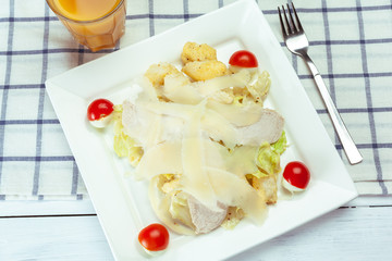 Caesar salad with chicken and greens on wooden table