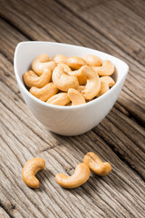 roasted cashew nuts in mini bowl on old wood