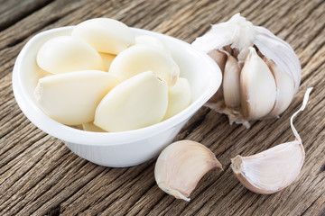 garlic clove and peeled in white ceramic cup on old wood