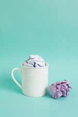 Creative concept, Crumpled paper in coffee cup on blue background.