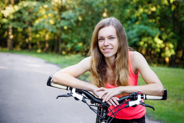 Fototapeta na wymiar Smiling sport woman with the bike standing on the road