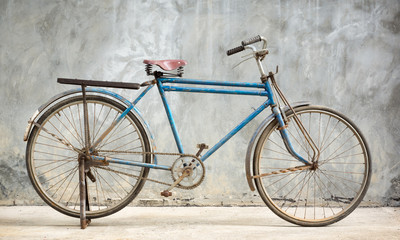 Old and rusty bicycle with grunge cement plaster wall background
