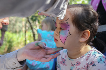 Cute girl getting face paintied as a butterfly