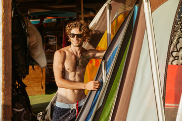 Professional young surfer getting surf board ready to catch waves - obrazy, fototapety, plakaty