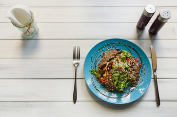Restaurant food top view on white wood. Warm meat salad