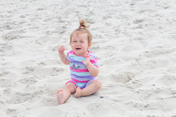 Crying baby girl,lonely cute baby girl sitting and crying in the sand