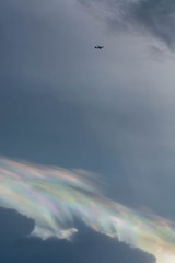 Irisation or iridescent cloud with airplane