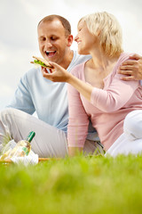 Mature woman treating her husband with sandwich