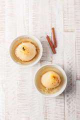 Homemade stuffed or baked pear with white wine, honey and nuts in a bowl, top view