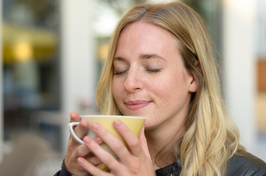 Blissful young woman enjoying coffee