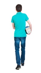 Back view of going  handsome man carries a stack of books. walking young guy . Rear view people collection.  backside view of person.  Isolated over white background. Sad man in a green T-shirt goes