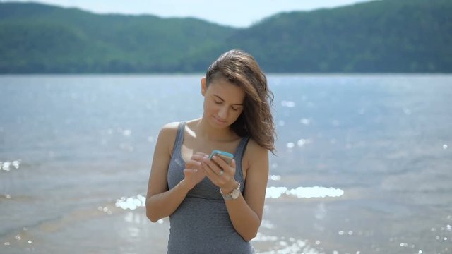 A young beautiful lady booking a hotel while standing at a beach