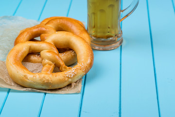 Beer mug and pretzel on blue wooden table.