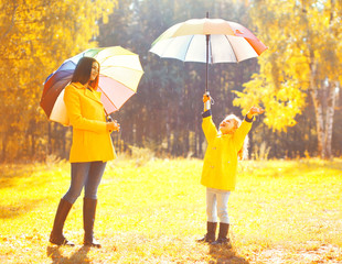 Moment of happiness! Happy family with umbrellas in sunny autumn