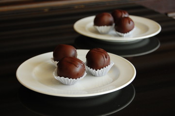 Assorted dark chocolate truffles with cocoa powder, coconut and chopped hazelnuts on a dessert plate