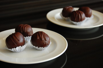 Assorted dark chocolate truffles with cocoa powder, coconut and chopped hazelnuts on a dessert plate