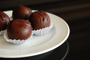 Assorted dark chocolate truffles with cocoa powder, coconut and chopped hazelnuts on a dessert plate