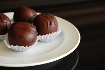 Assorted dark chocolate truffles with cocoa powder, coconut and chopped hazelnuts on a dessert plate