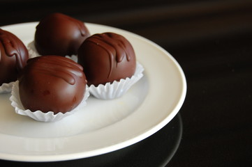 Assorted dark chocolate truffles with cocoa powder, coconut and chopped hazelnuts on a dessert plate