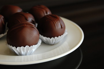 Assorted dark chocolate truffles with cocoa powder, coconut and chopped hazelnuts on a dessert plate