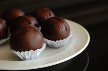 Assorted dark chocolate truffles with cocoa powder, coconut and chopped hazelnuts on a dessert plate