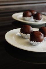 Assorted dark chocolate truffles with cocoa powder, coconut and chopped hazelnuts on a dessert plate