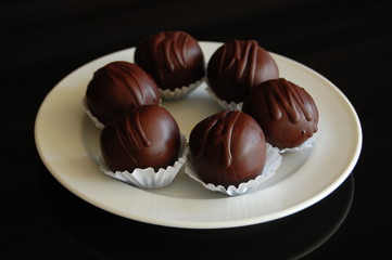 Assorted dark chocolate truffles with cocoa powder, coconut and chopped hazelnuts on a dessert plate