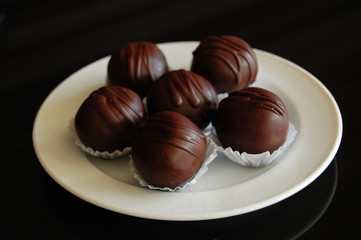 Assorted dark chocolate truffles with cocoa powder, coconut and chopped hazelnuts on a dessert plate