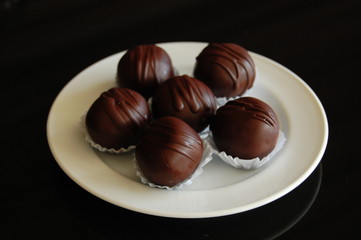Assorted dark chocolate truffles with cocoa powder, coconut and chopped hazelnuts on a dessert plate