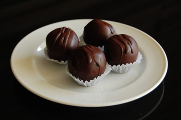 Assorted dark chocolate truffles with cocoa powder, coconut and chopped hazelnuts on a dessert plate