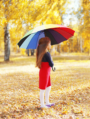 Little girl child with colorful umbrella dreaming in sunny autum