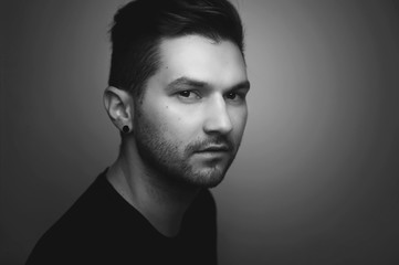 Black and white portrait of a serious young hipster handsome man looking at you, side view.