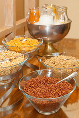 Buffet variety of cereals for breakfast-cereals in glass bowls, milk and juice in glass pitchers, vertical