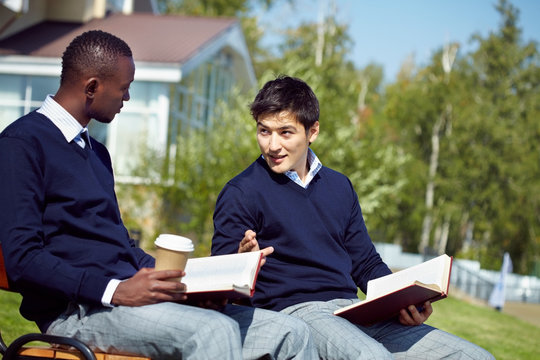Two young men sitting with books and communicating