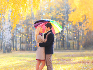 Happy loving couple with colorful umbrella in warm sunny day ove