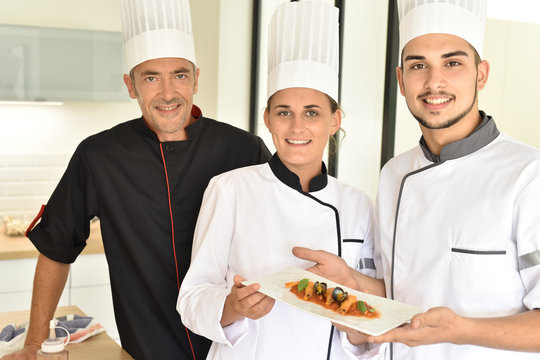 Young chefs presenting dish to teacher