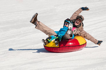 Plaisir d& 39 hiver. Jeune femme et petit garçon glissant en descente sur un tube de neige